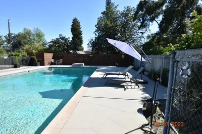 a pool with a chair and an umbrella next to it at Spacious pool home in Pasadena in Pasadena