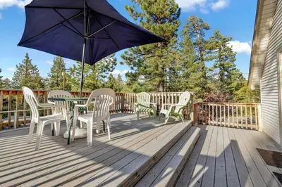 a patio with a table and chairs and an umbrella at Pine Nest Relaxing Walk to Marina Cozy Chalet in Big Bear Lake