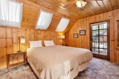 a bedroom with a bed in a room with wooden walls at Pine Nest Relaxing Walk to Marina Cozy Chalet in Big Bear Lake
