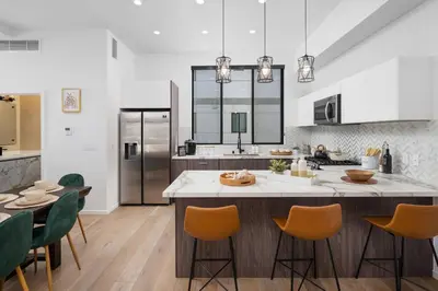 a kitchen with a large island in a kitchen with green chairs at Modern Hollywood Charm in Los Angeles