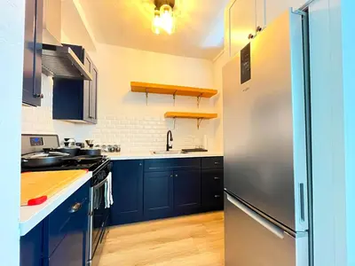 a kitchen with blue cabinets and a stainless steel refrigerator at Heart of Hollywood Apartment - 2Bed 2Bath in Los Angeles