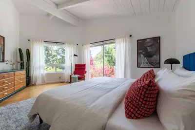 a bedroom with a large white bed with red pillows at Stunning Hollywood Midcentury Modern-Views-Best Location! in Los Angeles