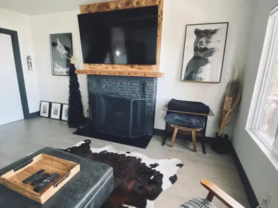 a living room with a fireplace and a flat screen tv at The Inspo Cabin with Stunning View in Running Springs