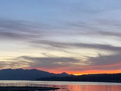 a sunset over a body of water with mountains in the background at Village and Lake Escape - Walk to the Lake and Village in Big Bear Lake