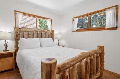 a bedroom with a wooden bed and two windows at Village and Lake Escape - Walk to the Lake and Village in Big Bear Lake