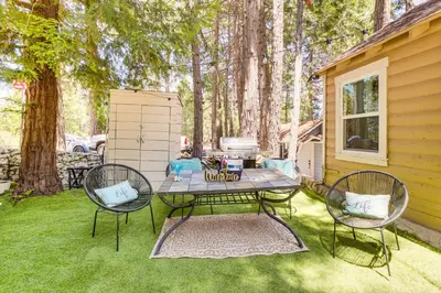a patio with a table and two chairs on the grass at Pet-Friendly California Abode with Fenced-In Yard! in Crestline