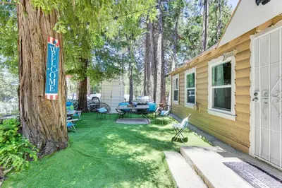 a backyard with a tree and a table and chairs at Pet-Friendly California Abode with Fenced-In Yard! in Crestline