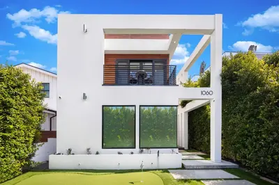 a white house with a green yard at The Palms Pad - 5 Min from Beach - Golf,Arcade,Sauna in Los Angeles