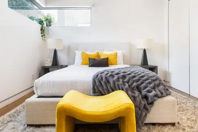 a bedroom with a bed with a yellow ottoman at The Palms Pad - 5 Min from Beach - Golf,Arcade,Sauna in Los Angeles