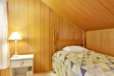 a bedroom with a bed in a room with wooden walls at Pinglewood Cabin- Furnished Fawnskin Group Retreat in Fawnskin
