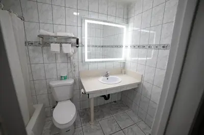 a bathroom with a toilet and a sink and a mirror at Artesia Motor Inn in Bellflower
