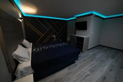 a bedroom with a bed with a blue light on it at Artesia Motor Inn in Bellflower