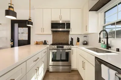 a kitchen with white cabinets and a stainless steel stove at Downtown Culver City New Designer Lux 1 Bedroom in Los Angeles