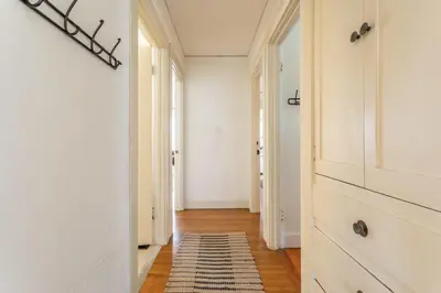 a hallway with white walls and a rug on a wooden floor at Hermosa Bungalow 1920s Charm Steps to the Strand in Hermosa Beach