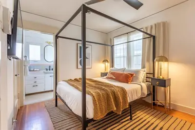 a bedroom with a canopy bed and a bathroom at Hermosa Bungalow 1920s Charm Steps to the Strand in Hermosa Beach