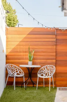 two chairs and a table on a patio with a fence at Vibe on the Patio at a Modern Luxury Studio near LAX Beach in Los Angeles