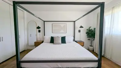 a bedroom with a canopy bed with white sheets and pillows at LA Huge Mid Century Guesthouse Patio LAX Beach in Los Angeles
