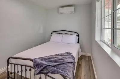 a bed with a blanket on it in a room with windows at Sleek San Fernando Studio about 14 Mi to Universal in San Fernando