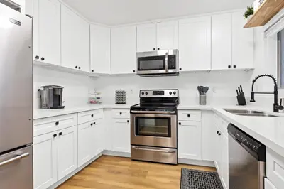 a white kitchen with stainless steel appliances and white cabinets at Double King Suite with Patio Dining and Parking NRP21-00386 in Long Beach