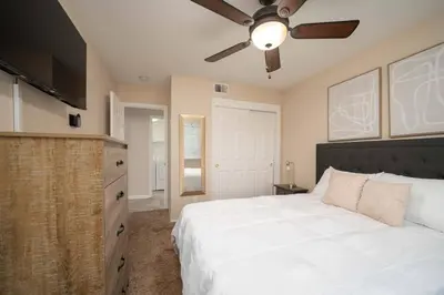 a bedroom with a white bed and a ceiling fan at Families/Digital Nomads/Corporate Housing in Bakersfield