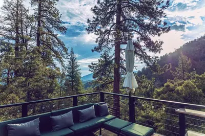 a couch on a balcony with a view of the mountains at Spectacular Designer Treehouse with Mountain Views in Pine Mountain Club