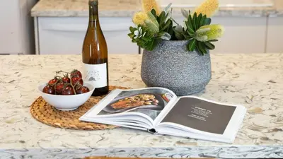 a table with a book and a bottle of wine at Southwest by AvantStay in Los Angeles