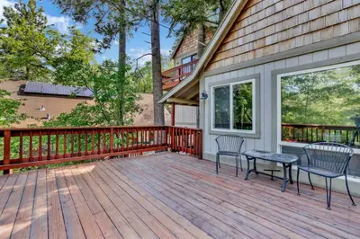 a wooden deck with two chairs and a table at Knickerbocker Retreat- Hot Tub- Game Tables in Big Bear Lake