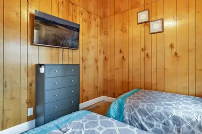 a bedroom with wood paneled walls and a bed at Sweet Retreat Combo- Relaxing Resort Cottage Combo in Big Bear Lake