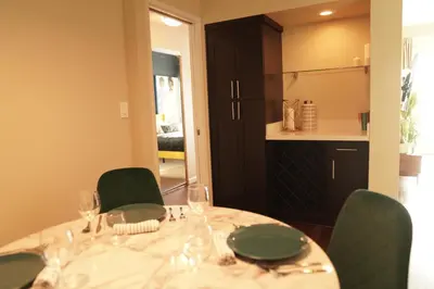 a dining room table with green chairs and a kitchen at Lux Oasis in West Hollywood, Free Parking & Swimming pool in Los Angeles
