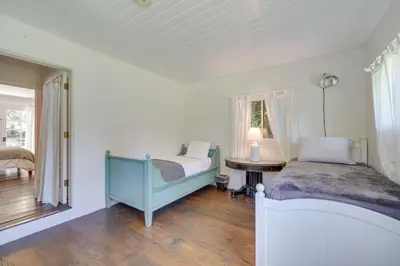 a bedroom with a bed and a table and a window at Farmhouse-Chic Carpinteria Cottage with Pool Access in Carpinteria