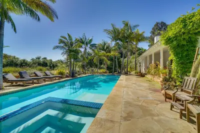a swimming pool with chairs and a house at Farmhouse-Chic Carpinteria Cottage with Pool Access in Carpinteria