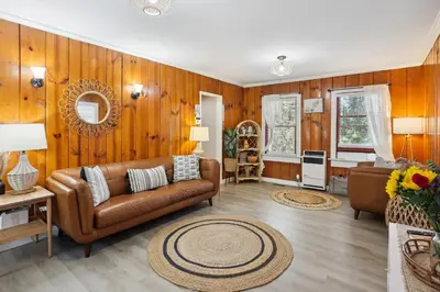 a living room with a brown couch and wooden walls at Twin Peaks Vacation Rental with Hot Tub! in Twin Peaks