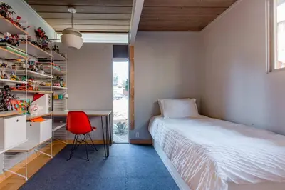 a bedroom with a bed and a desk and a red chair at Eichler Mid Century Modern Designer Pool/Jacuzzi in Thousand Oaks