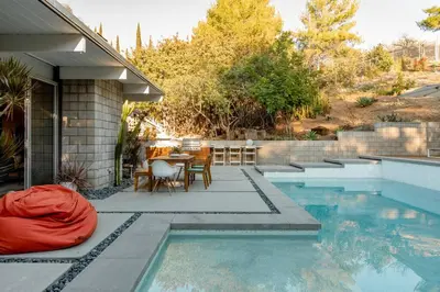 a swimming pool with a table and chairs next to a house at Eichler Mid Century Modern Designer Pool/Jacuzzi in Thousand Oaks