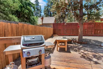 a grill and picnic table in a backyard with a fence at Maltby Modern Log Cabin Relaxing Chalet Retreat in Big Bear Lake