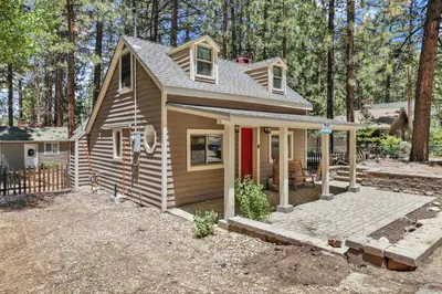 a small house with a red door in the woods at Moonridge R n R- Cozy Single Level Central Chalet Home in Big Bear Lake