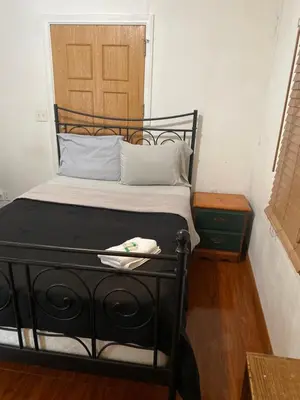 a bedroom with a black bed with a wooden door at House Rooms & RV Rooms Near LAX in Los Angeles