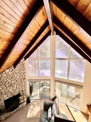 a large living room with a stone wall at Family Friendly A Frame, Pets stay Free! in Lake Arrowhead