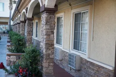 a brick building with windows and flowers on a sidewalk at Avenue Motel in Gardena