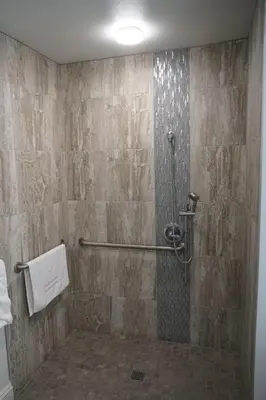 a bathroom with a shower with a tile wall at Avenue Motel in Gardena