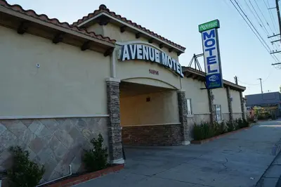 a building with a sign that reads arrive inn at Avenue Motel in Gardena