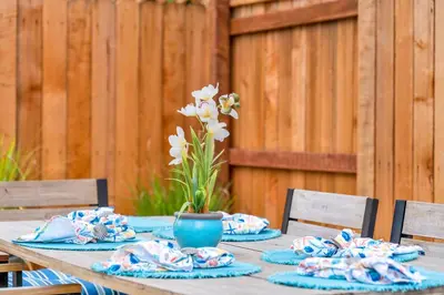 a wooden table with blue napkins and a vase of flowers at Retro Cottage, Hot Tub, Putting Green, walk to all in Thousand Oaks
