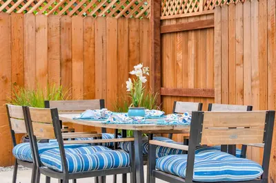 a wooden fence with a table and four chairs at Retro Cottage, Hot Tub, Putting Green, walk to all in Thousand Oaks