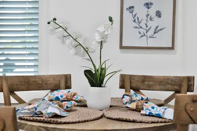 a table with two chairs and a vase with white flowers at Retro Cottage, Hot Tub, Putting Green, walk to all in Thousand Oaks