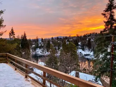 a sunset over a snowy field with a wooden fence at Beautiful Lake View House for rent! in Lake Arrowhead
