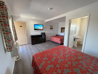 a hotel room with a red bed and a television at Palm Inn in Mojave