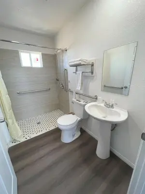a white bathroom with a toilet and a sink at Palm Inn in Mojave