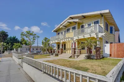 a yellow house with a white fence in front of it at 1 Mi to Dtwn! Bright Long Beach Apartment in Long Beach
