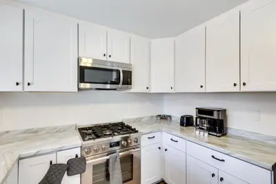 a kitchen with white cabinets and a stove top oven at Quiet Ridgecrest Vacation Rental with Private Yard! in Ridgecrest