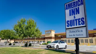 a sign for an emergency inn and suites in a parking lot at America Inn & Suites in Ridgecrest